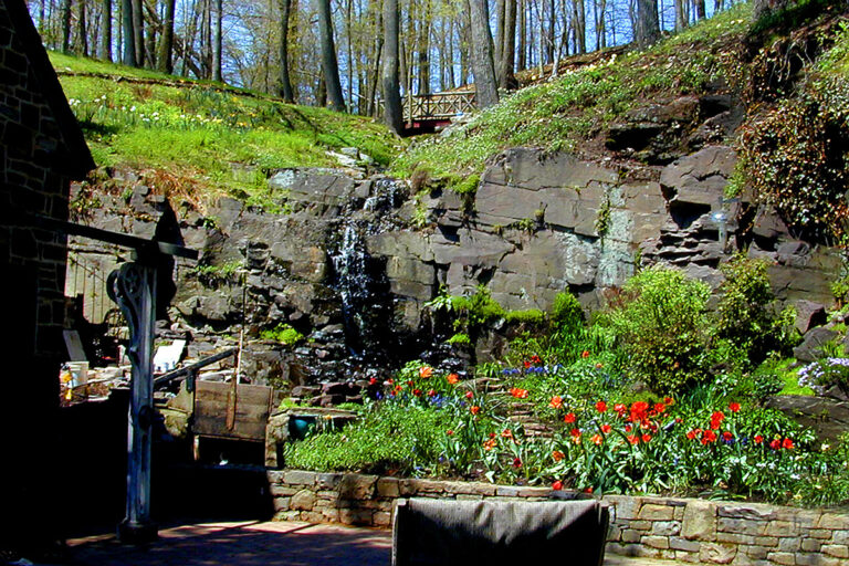 Patio with containers and waterfall over stone wall